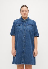 Denim jurk, met korte mouwen, lichtblauw, met een knoopsluiting aan de voorkant, twee borstzakken en een gebogen zoom. Zachte textuur met een casual ontwerp.