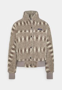 Chaqueta de forro polar con estampado marrón y crema, cuello con cremallera, parte frontal con botones, y puños y dobladillos acanalados. Presenta un parche con el logo en el pecho.