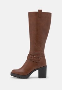 Snelle bruine leren kniehoge laars met een getextureerde gevlochten riem, blokhak en een gladde afwerking. Voorzien van een trekband voor eenvoudig aan- en uittrekken.