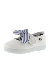 Zapatilla de lona blanca con suela de goma gris y un lazo a rayas azules y blancas. Cuenta con una correa de Velcro y un logo en el lateral.