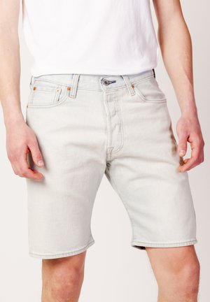 Shorts en denim bleu clair avec une coupe droite, cinq poches et des accents en rivets en cuivre. Le matériau semble doux avec une légère variation de texture.