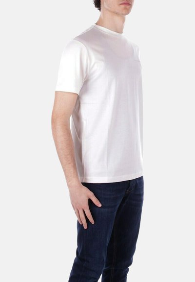 T-shirt bianco a maniche corte in tessuto morbido, con scollatura rotonda e vestibilità rilassata, abbinato a jeans scuri. Design minimalista.