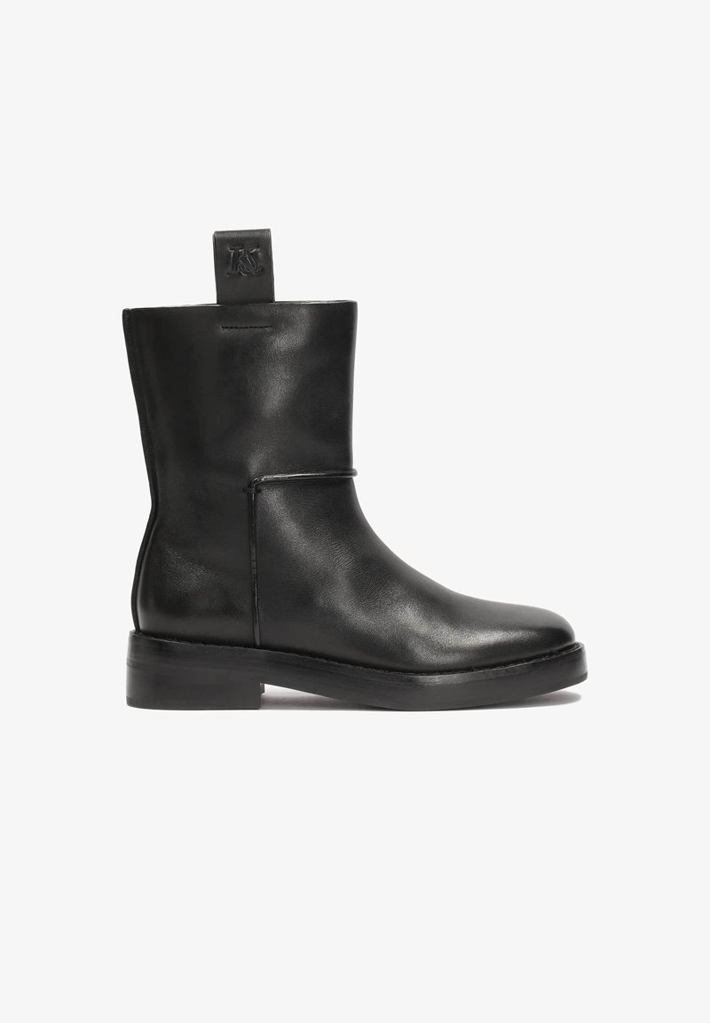 Bottine en cuir noir avec bout rond, talon bas, et languette à tirer présentant un logo embossé.
