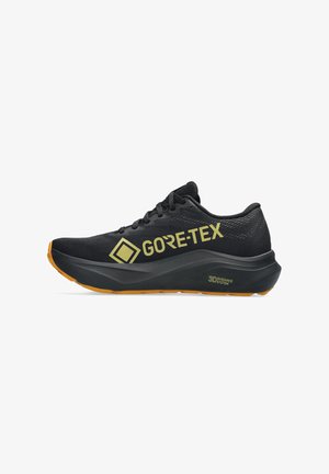 Shoe de corrida preto com o logótipo "GORE-TEX" amarelo, parte superior em tecido texturizado, colarinho acolchoado e sola de borracha laranja para tração.