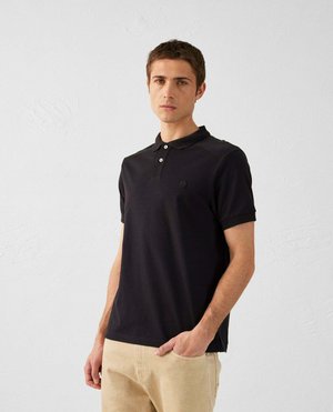 Zwarte poloshirt met korte mouwen, drie-knopen sluiting en een klein logo. Gecombineerd met lichtbeige broeken, tegen een neutrale achtergrond.