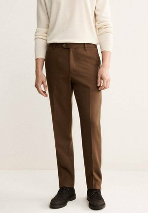 Pantaloni marroni su misura con una texture liscia e una silhouette dritta. Presentano un singolo bottone frontale e passanti per cintura. Indossati con un maglione color crema.