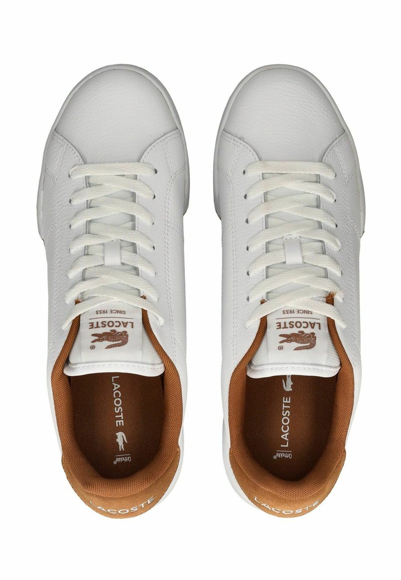 Baskets blanches en cuir avec une finition texturée, lacets blancs plats, accents en daim marron sur le col et logo Lacoste sur la languette.