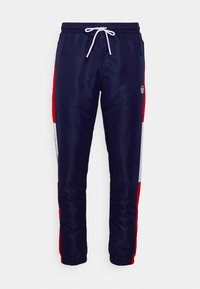 Pantalones deportivos navy con paneles laterales en rojo y blanco, cinturilla elástica con cordón y puños elásticos. Presenta un logo en el muslo izquierdo.