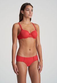 Czerwony zestaw bielizny składający się z usztywnianego biustonosza o kratkowanej strukturze, ramiączek ozdobionych kwiatami oraz pasujących majtek w stylu hipster.