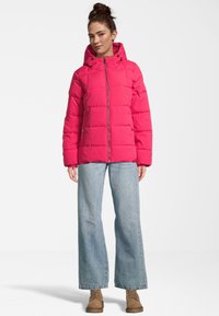 Rosa gepolsterte Jacke mit Reißverschluss und Kapuze. Verfügt über ein gestepptes Design und Taschen. Tragen über weiten hellblauen Jeans und braunen Stiefeln.