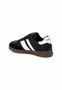 Sneaker neri con strisce bianche, dotati di una tomaia in pelle liscia, dettagli testurizzati e una suola in gomma marrone. "TEDDY" è stampato sul tallone.