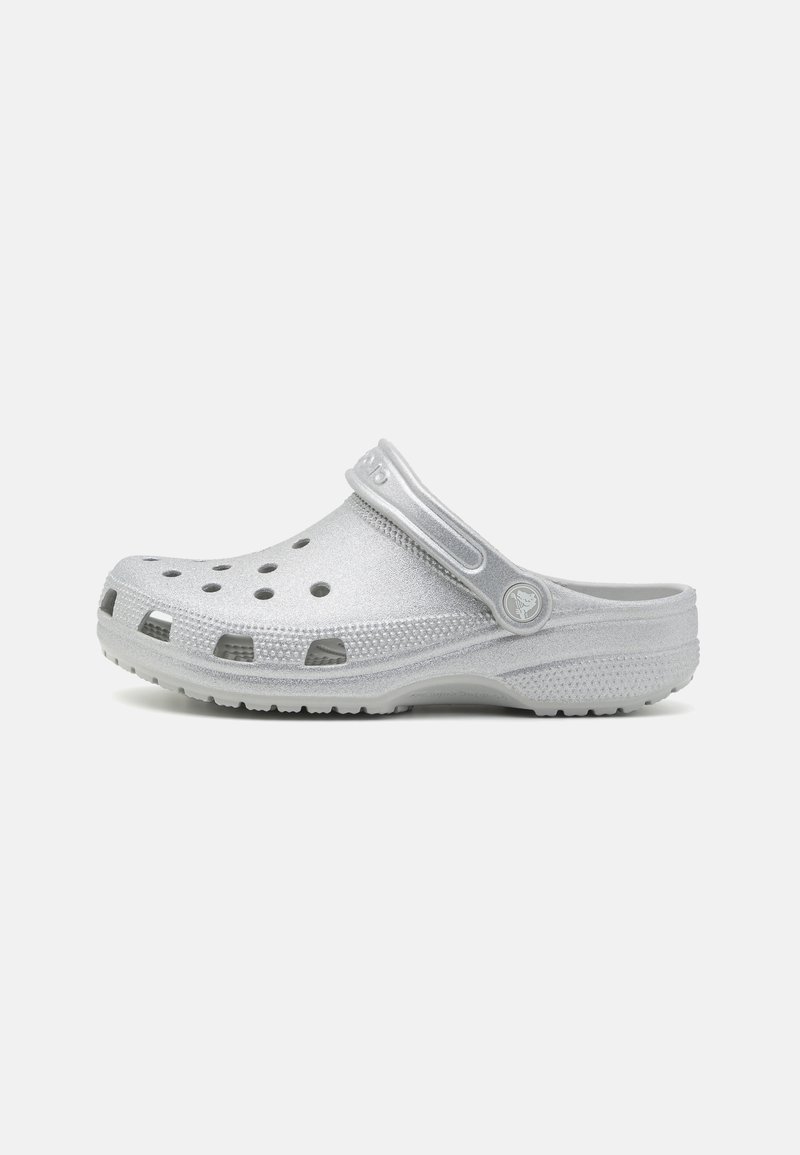 Silberner Clog-Schuh aus leichtem Material, mit Belüftungsöffnungen, strukturierter Oberfläche und einem Riemen für einen sicheren Sitz.