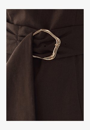 Brauner Stoffgürtel mit einer silbernen, unregelmäßig geformten Schnalle mit glatter Oberfläche, die durch eine Stoffschlaufe gesichert ist.