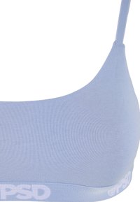 Coque de soutien-gorge bleu clair sans couture avec bretelle fine et bande élastique de marque au bas.