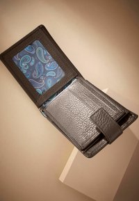 Portefeuille en cuir gris foncé, avec un intérieur à motif paisley. Comprend des emplacements pour cartes, une fenêtre transparente pour l'identité et une fermeture à pression.
