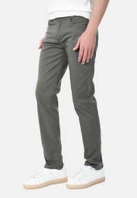Pantaloni slim-fit da uomo in cotone verde oliva, con cinque tasche, una texture liscia e un design a gamba affusolata.