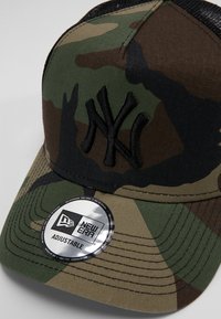 Camo-Baseballkappe mit gebogenem Schild, verstellbarem Riemen und gesticktem NY-Logo in Schwarz. Hergestellt aus einem Baumwoll-Mischgewebe mit Netzrücken.