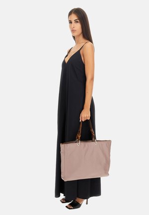 Borsa a tracolla beige con manici in pelle marrone, chiusura con zip, forma rettangolare e superficie liscia. Il modello indossa un abito lungo nero.