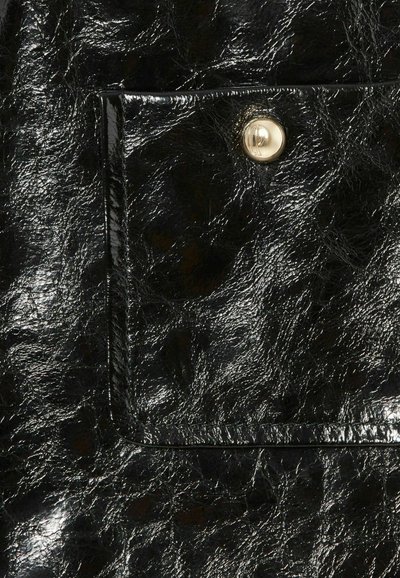 Bolso de charol negro con una superficie texturizada. Presenta un bolsillo plano y un botón de presión dorado, que ofrece un contraste con el material.