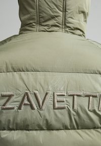 Πίσω όψη ενός χοντρού μπουφάν σε ελιά πράσινο χρώμα με κουκούλα και μεγάλο κεντημένο κείμενο "ZAVETTI" στην πάνω πλάτη.