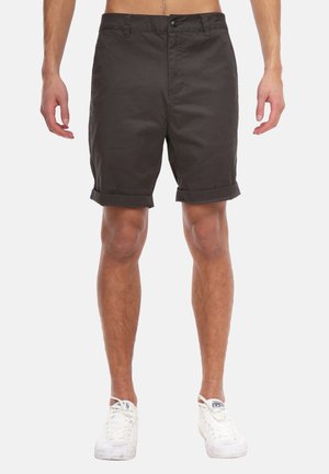 Schwarze Shorts aus strukturiertem Stoff, mit einem Knopfverschluss, umgeschlagenen Säumen und geradem Schnitt. Getragen mit weißen Sneakers.