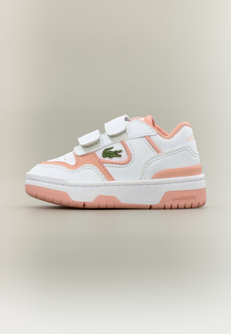 Παιδικό αθλητικό παπούτσι σε λευκό και ροζ χρώμα με δύο λουράκια βέλκρο και πράσινο λογότυπο κροκοδείλου στο πλάι, σε ουδέτερο φόντο.