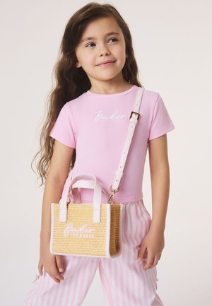 Tüdruk kannab roosat särki ja triibulisi pükse, õlal punutud beežist käekotti valge äärisega.