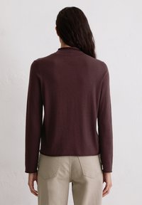 Bordeauxrood langarmshirt met een ronde halslijn, een gladde textuur en een rechte zoom, gedragen met licht kaki broek.