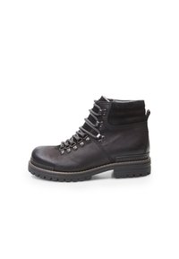 Botas de cuero negras hasta el tobillo con un acabado texturizado, diseño con cordones, herrajes metálicos y suelas de goma que presentan un patrón de tracción resistente.