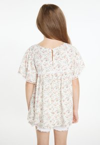Blomsterbluse i let stof med korte ærmer, med en nøglehulslukning i ryggen, spidsdetaljer i blonder og små lyserøde og grønne blomster mønstre.