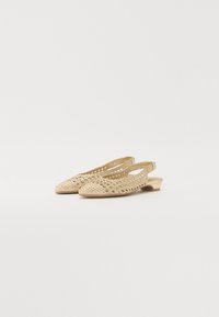 Chaussures slingback dorées avec un design en tissage ouvert, bout pointu et petit talon bloc, présentant une texture lisse et des accents minimalistes.
