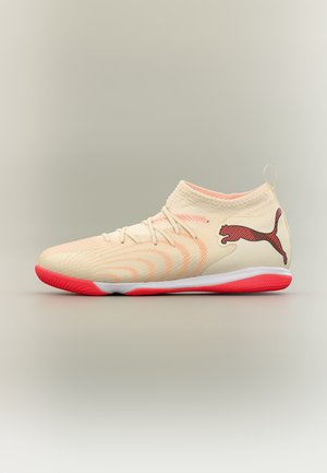 Αθλητικό παπούτσι Puma σε κρεμ και κοραλί, ψηλό, με κόκκινη σόλα και λογότυπο Puma στο πλάι, με φόντο ανοιχτό γκρι.