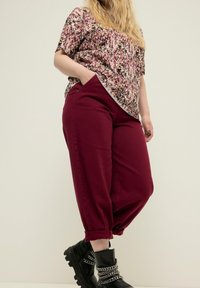 Bordo rento-hatut jatkuvat housut ja kaarrokkeet lyhyt hiha pusero purppura- ja beige sävyissä. Mustat nilkkurit, joissa on ketjuviimeistely.