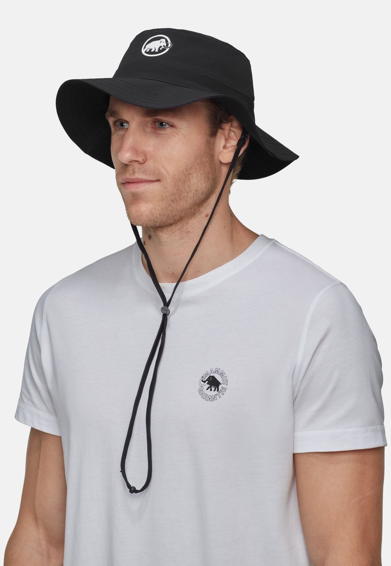 Schwarzer Bucket-Hut mit breiter Krempe, der auf der Vorderseite ein Logo-Patch und einen Kinnriemen hat. Der Stoff wirkt leicht und flexibel.