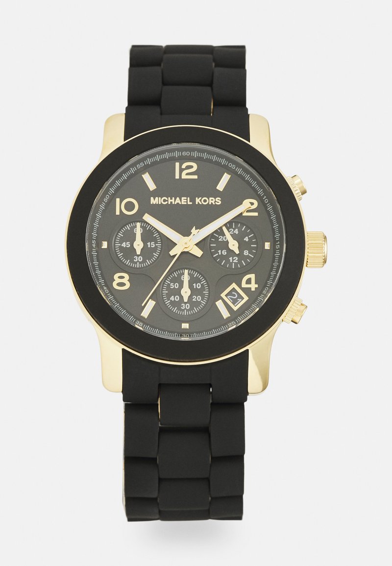 Reloj Michael Kors con correa de silicona negra, caja de acero inoxidable en tono dorado, esfera negra, marcadores de hora dorados y tres subesferas.
