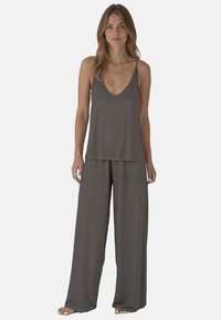 Comodo completo a due pezzi composto da un top grigio senza maniche con scollo a V e pantaloni ampi e larghi realizzati in tessuto morbido.