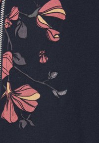 Tejido azul marino con un patrón floral en rosa y amarillo, con pétalos y hojas detallados, complementado por un zipper plateado.