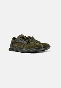 Zapatillas de gamuza verde oliva con parte superior de malla gris texturizada, cordones redondos y una suela de goma flexible que presenta un patrón de diseño único.