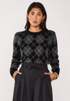 Maglione argyle nero e grigio con scollatura tonda, maniche lunghe e polsi a costine, abbinato a pantaloni grigi a vita alta con pieghe.