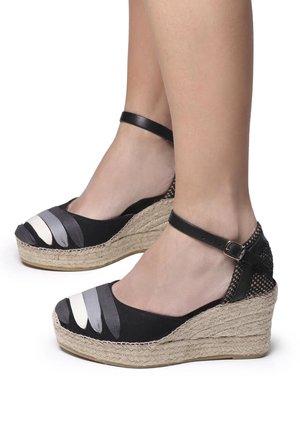 Le zeppe espadrille nere presentano una suola intermedia in juta intrecciata, una fascia per la caviglia e una punta in tessuto con strisce alternanti nere e grigie.