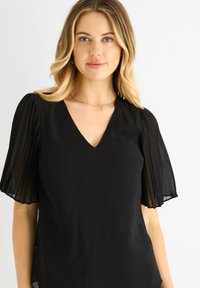 Black blouse with short, pleated sheer sleeves and a V-neck. Soft fabric with a smooth texture, featuring a classic, fitted design.