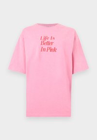 Ροζ κοντομάνικη μπλούζα με κόκκινο κείμενο «Η ζωή είναι καλύτερη με ροζ» στο κέντρο μπροστά, πάνω σε απλό λευκό φόντο.