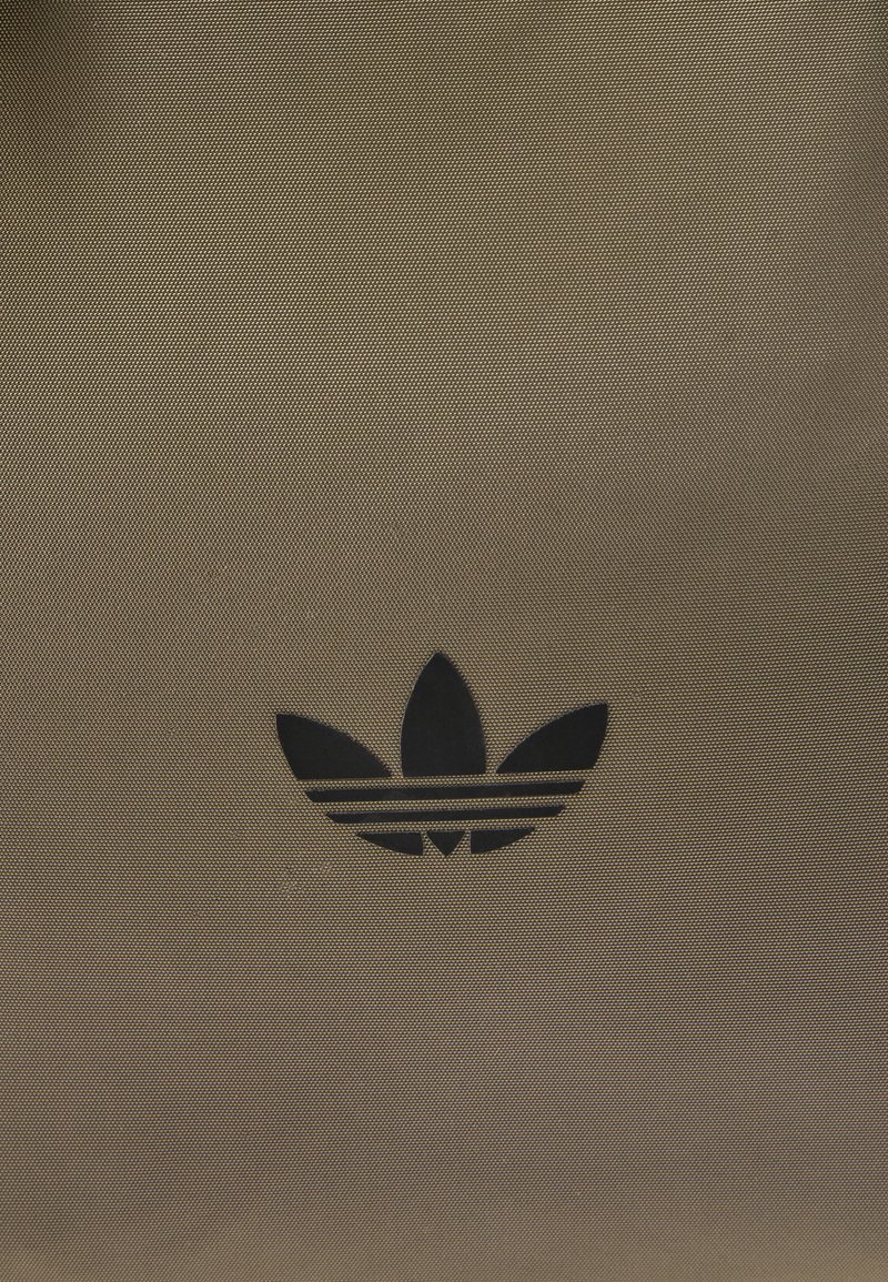 Brown textured fabric bag featuring a small black Adidas trefoil logo with three stripes underneath.