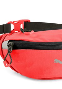 Bolsa de cintura de tejido rojo con una superficie texturizada, cremallera negra, correa ajustable negra y un logo gris prominente en el lateral.