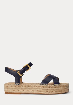 Tengerészkék bőrből készült platform szandál, keresztbe futó elülső pántokkal, arany csattal ellátott boka pánttal és fonott jutatalppal.