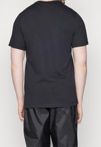 Svart bomullströja med korta ärmar, rundad hals och enkel design. Tyget har en mjuk struktur och går precis under midjan.