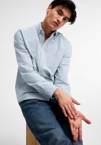 Lichtblauw gestreept overhemd met knopen, een kraag, lange mouwen en een borstzak, gecombineerd met donkerdenim jeans.