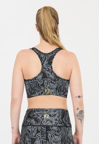 Grå mönstrad sportbh med racerback-design. Har en mjuk textur och en liten gul "FZ"-logotyp på baksidan nära nederkanten.
