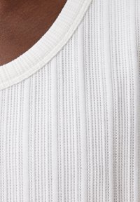 Weißer Rippstoff mit strukturierter Oberfläche und weitem Ausschnitt. Das Material weist abwechselnd dünne und dicke Streifen für visuelle Details auf.