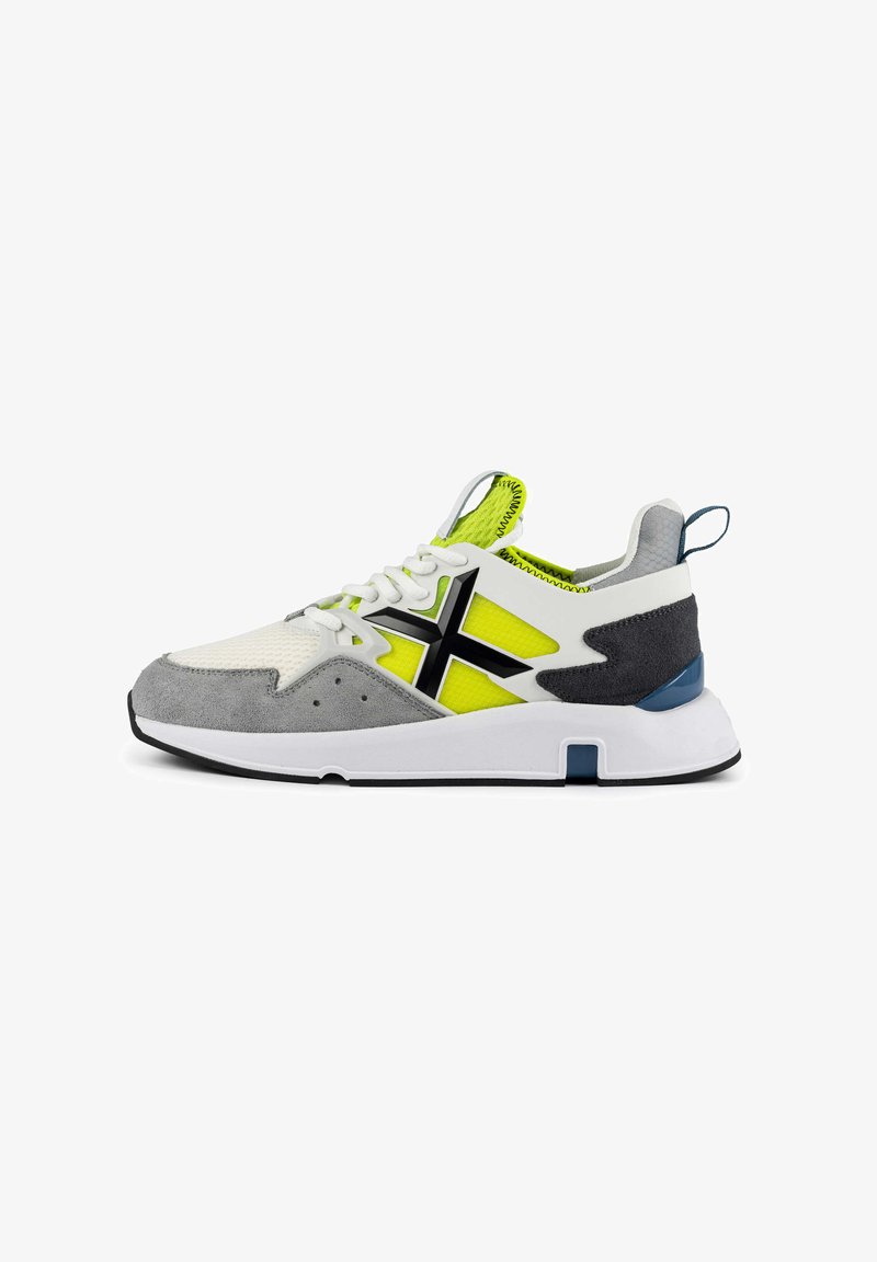 Sneaker mit einem weißen Mesh-Obermaterial, grauen Wildlederakzenten, schwarzem Logo, neon-gelben Einsätzen und einer weißen Sohle mit einem blauen Akzent an der Ferse.